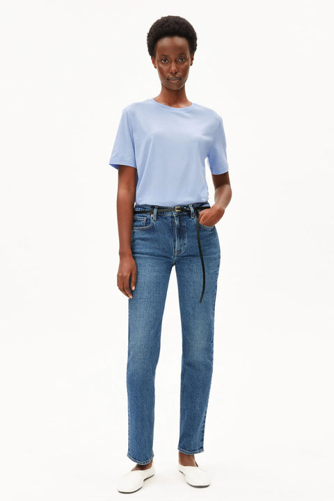 Model trägt das Lualaa T-Shirt in Soft Blue kombiniert mit Jeans und Gürtel
